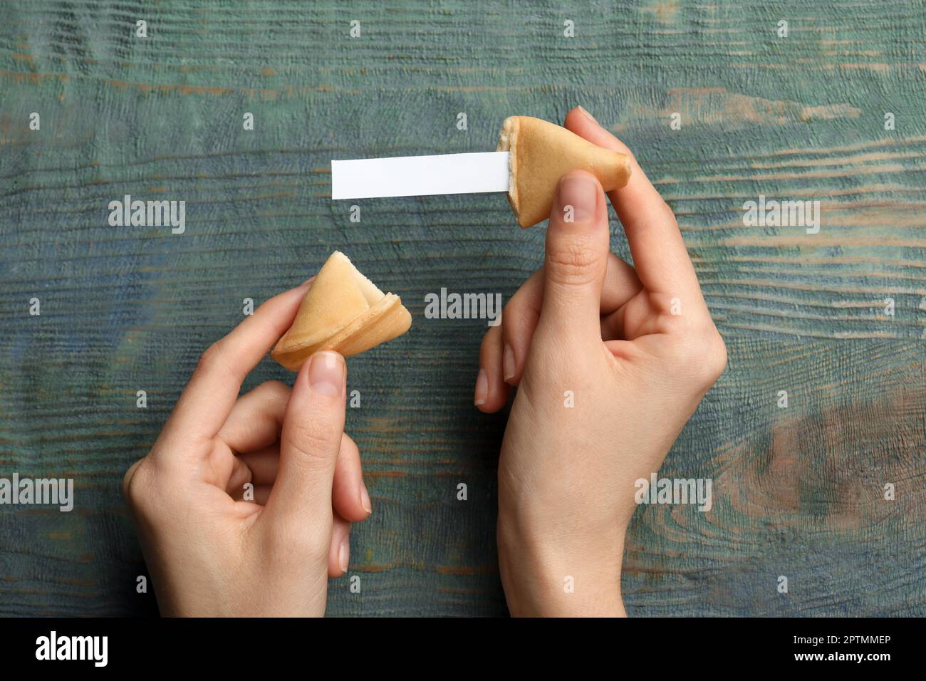 Eine Frau mit leckerem Glückskeks und Papier mit Vorhersage auf einem blauen Holztisch, Draufsicht. Platz für Text Stockfoto