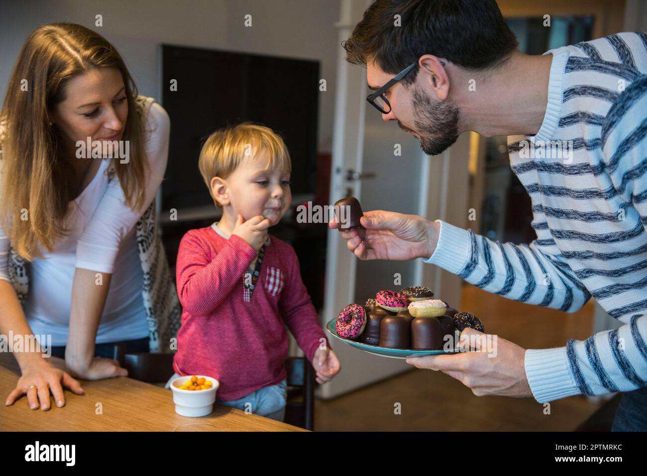 Vater, der seinem kleinen Sohn, München, Gebäck anbietet Stockfoto