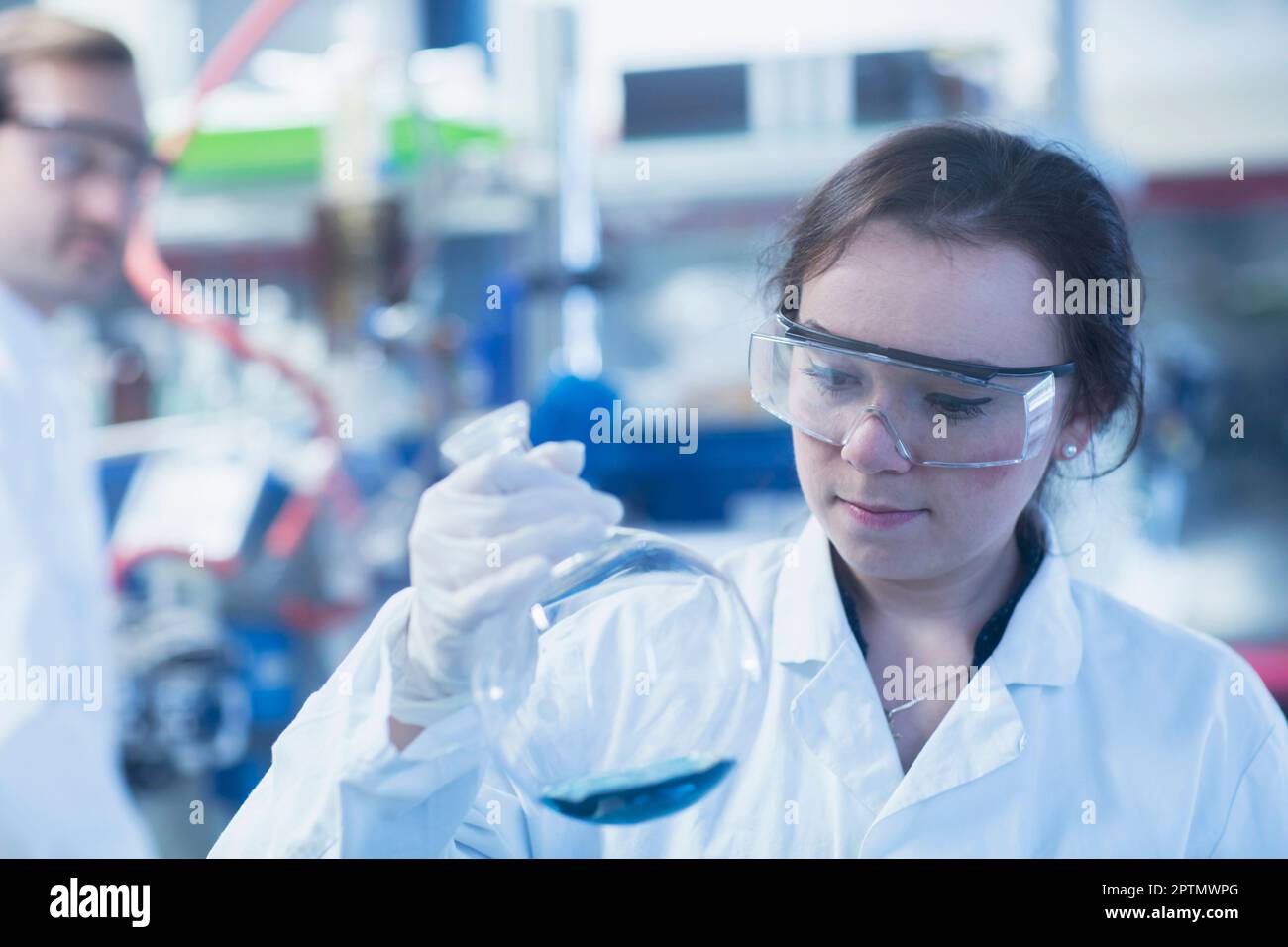 Junge Wissenschaftlerin, die den Kolben in einem Labor untersucht, Freiburg im Breisgau, Baden-württemberg, Deutschland Stockfoto