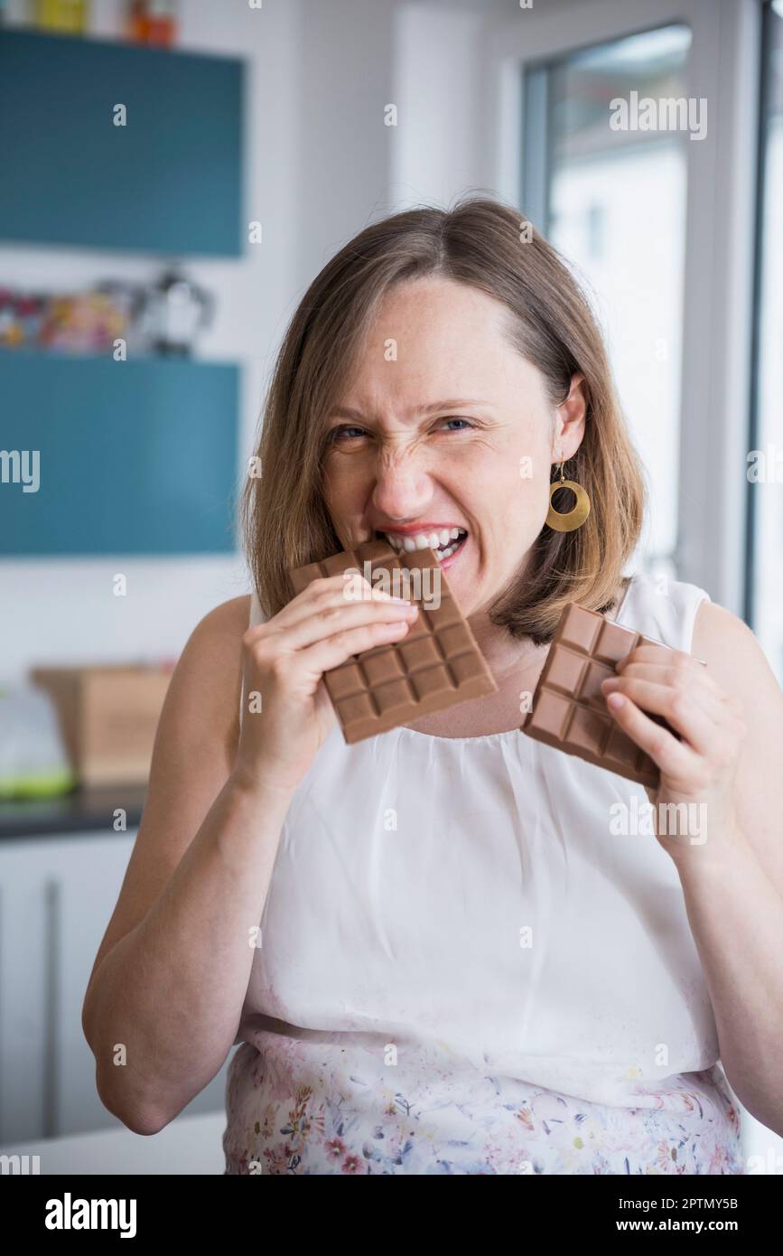 Porträt einer schwangeren Frau, die Schokolade in der Küche isst, München, Bayern, Deutschland Stockfoto