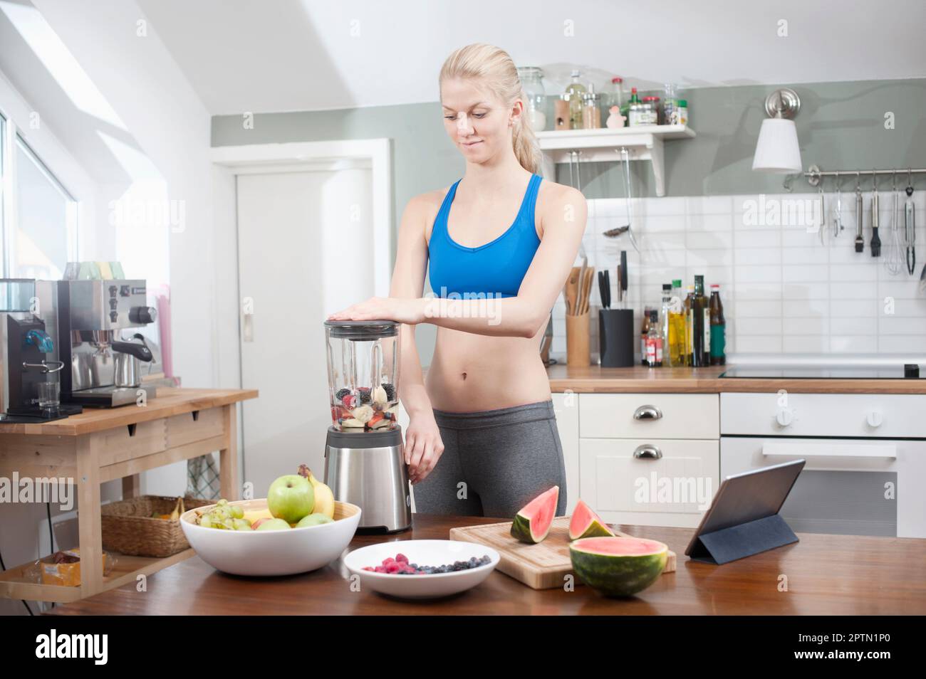 Junge Frau, die Smoothie in der Küche zubereitet, Bayern, Deutschland Stockfoto