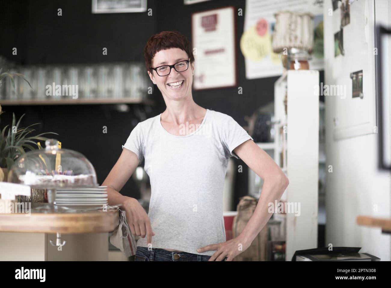 Reife Frau, die im Café steht und lächelt, Freiburg im Breisgau, Baden-Württemberg, Deutschland Stockfoto