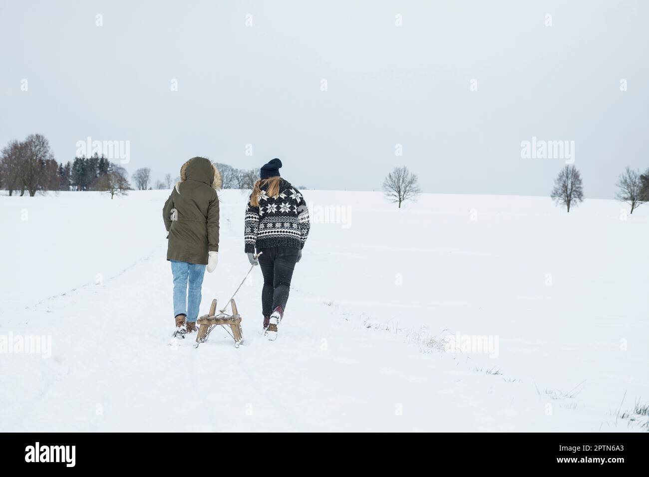 Zwei Mädchen im Teenageralter mit Schlitten in verschneiter Landschaft im Winter, Bayern, Deutschland Stockfoto