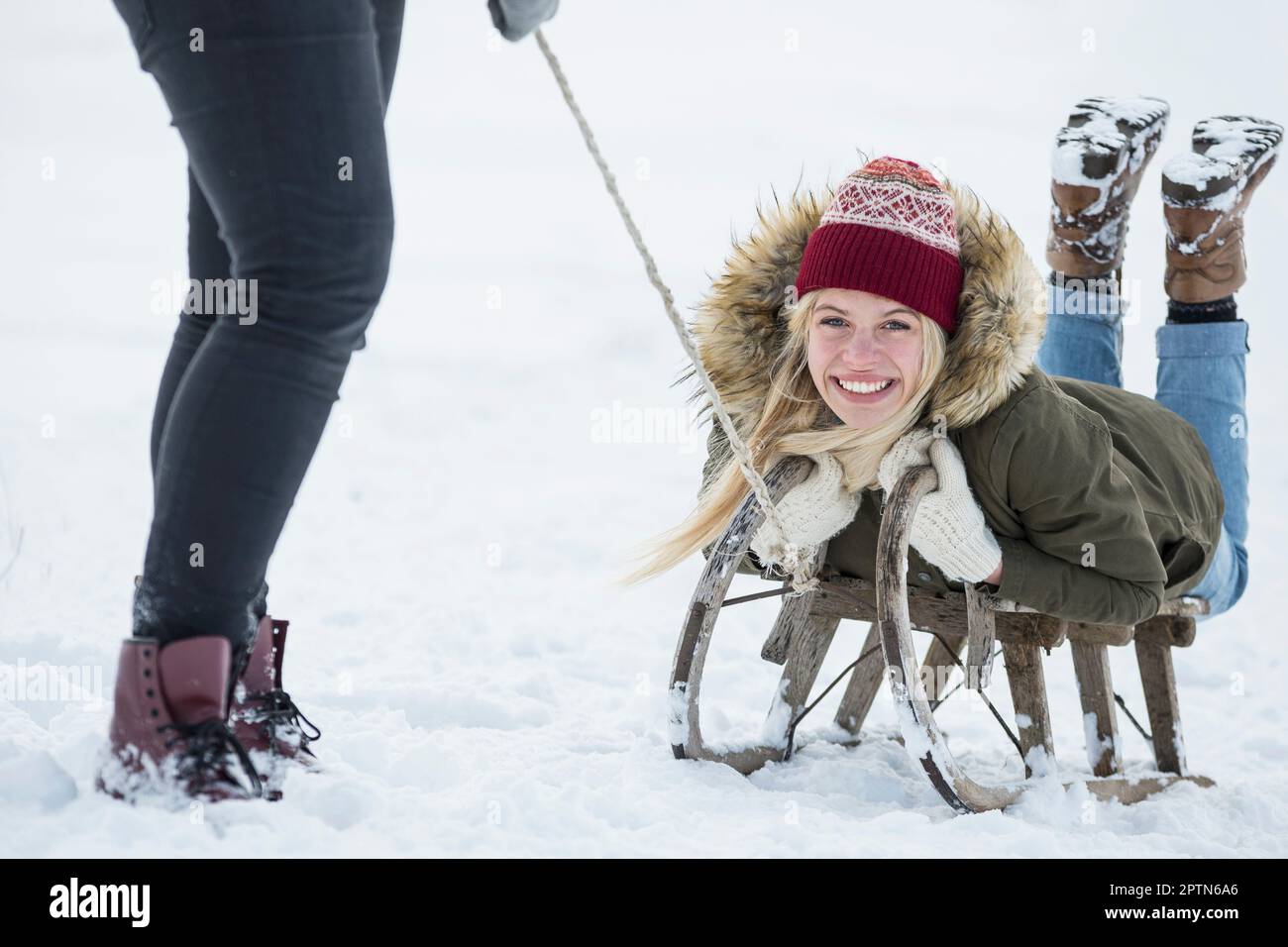 Zwei Mädchen im Teenageralter mit Rutsche in verschneiter Landschaft im Winter, Bayern, Deutschland Stockfoto