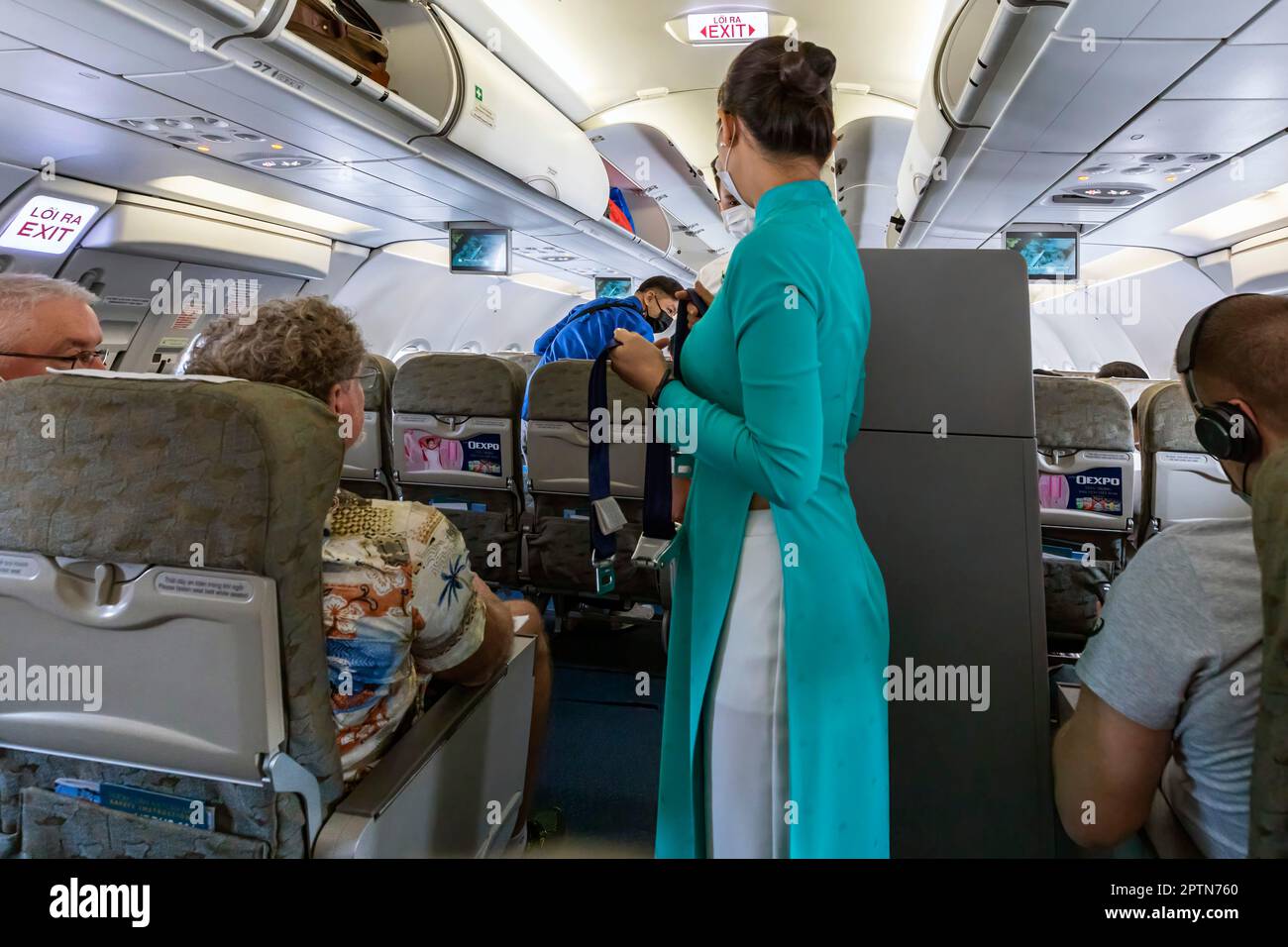 Vietnam Airlines Kabinenpersonal kümmert sich um die Passagiere, trägt AO dai Uniform auf dem Flug von Bangkok nach Vietnam Stockfoto