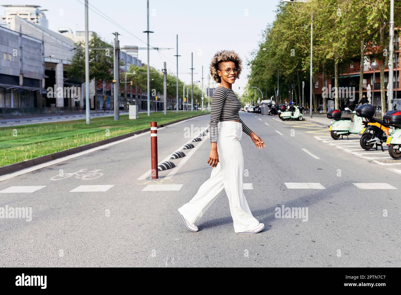 Rückansicht einer Frau in pinkfarbener Jacke, die die Straße entlang läuft Stockfoto
