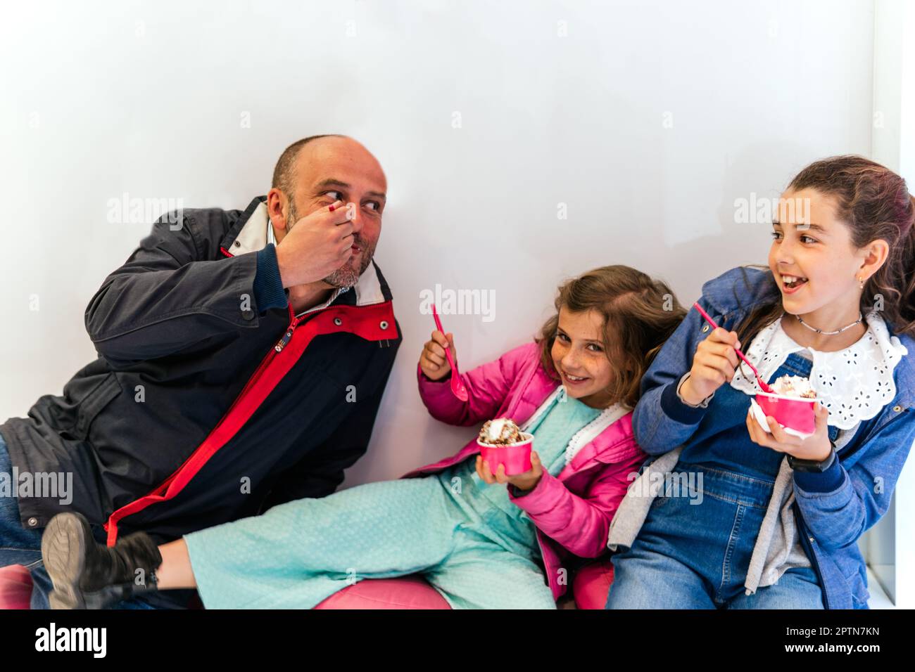 Zwei kleine Mädchen mit ihrem Vater, die Eis essen Stockfoto