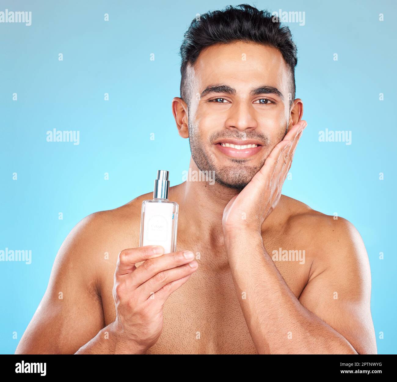 Porträt von Mann, Duft und Aftershave-Flasche für Hautpflege, Wellness und Luxuskosmetik auf blauem Hintergrund. Glücklicher junger indianer, männlicher Verehrer Stockfoto