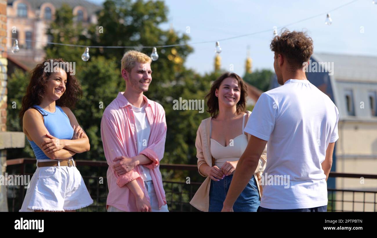 Porträt von glücklichen weißen, männlichen und weiblichen Freunden, die draußen zusammenstehen und sprechen. Freizeit. Junge Leute, die draußen plaudern und lächeln Stockfoto