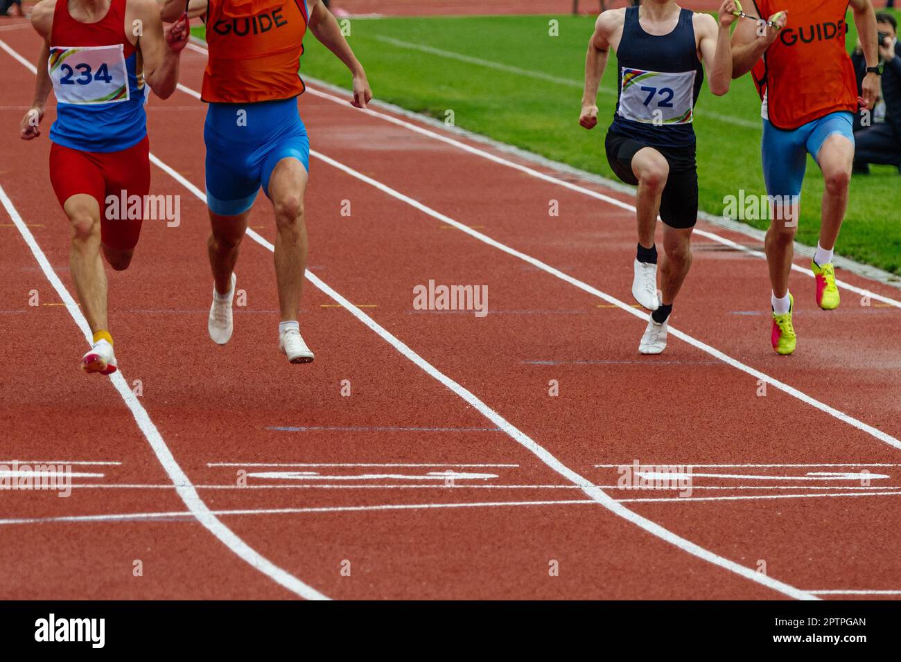 Männliche blinde para-Athleten mit Führern, die das Stadion der Ziellinie und die Sommer-Para-Athletik-Meisterschaften führen Stockfoto