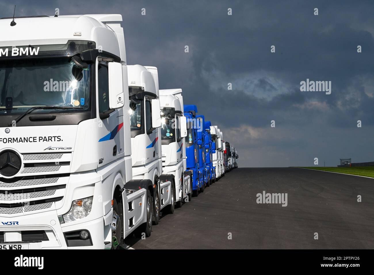 Eine Reihe von LKW-Taxis, parken Sie und Reihen Sie eine Asphaltfläche mit dem Sonnenschein nach unten, mit dem Hintergrund dunkler donnernder Wolken Stockfoto