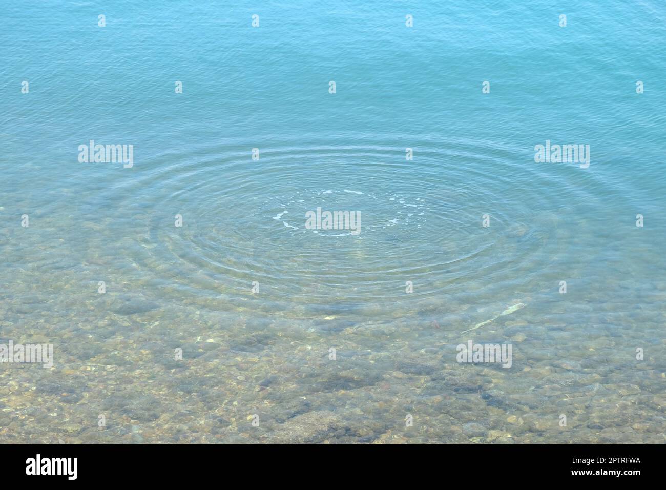 Runde Wassertropfen über den Kreisen auf dem Wasser. Wassertropfen, Wirbeln und Spritzen. Wellen auf dem Hintergrund des Meerestextur-Musters. Stockfoto
