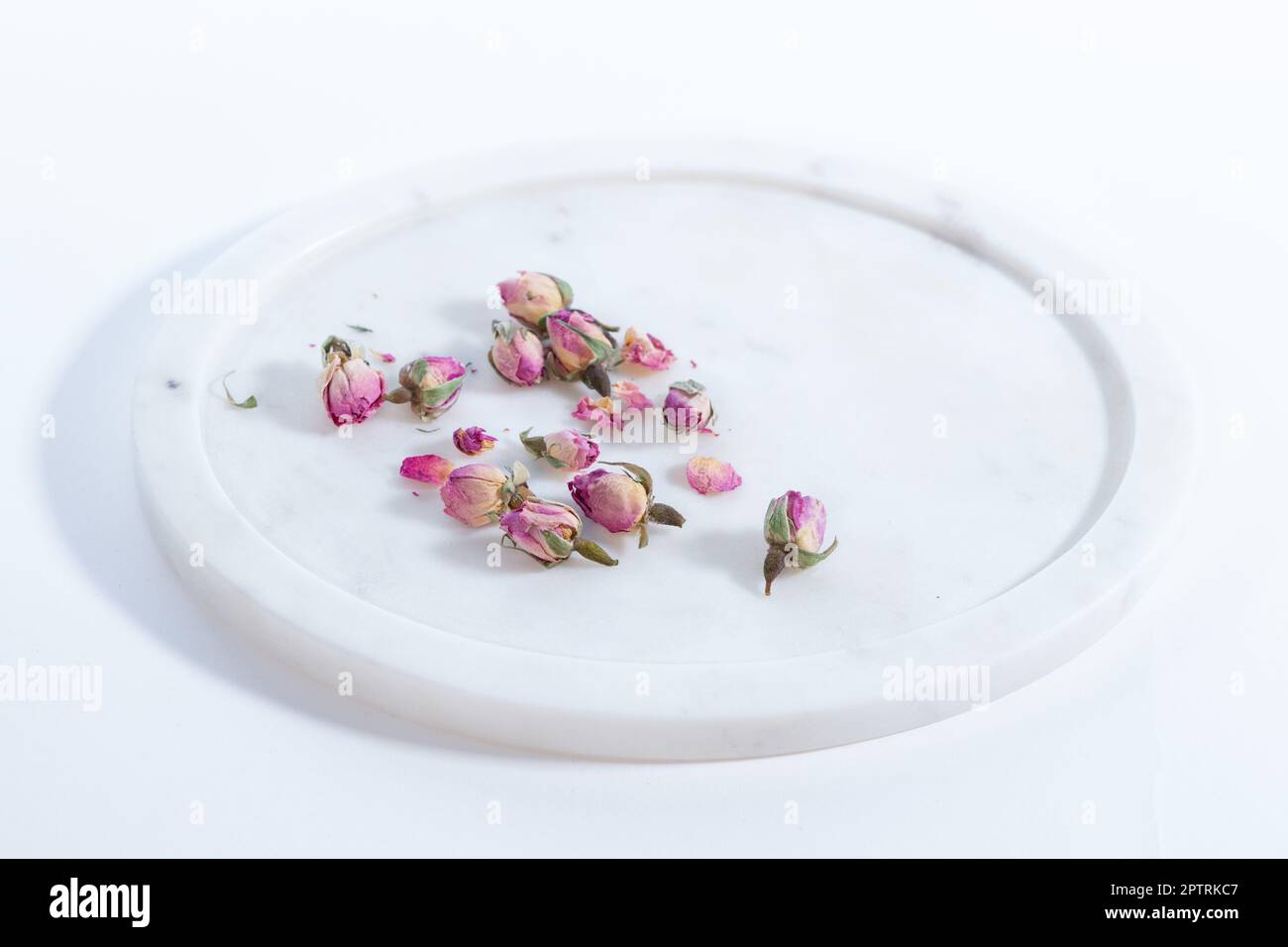 Schöne und rosafarbene kleine getrocknete Rosen auf weißem Hintergrund mit Marmorplatte Stockfoto