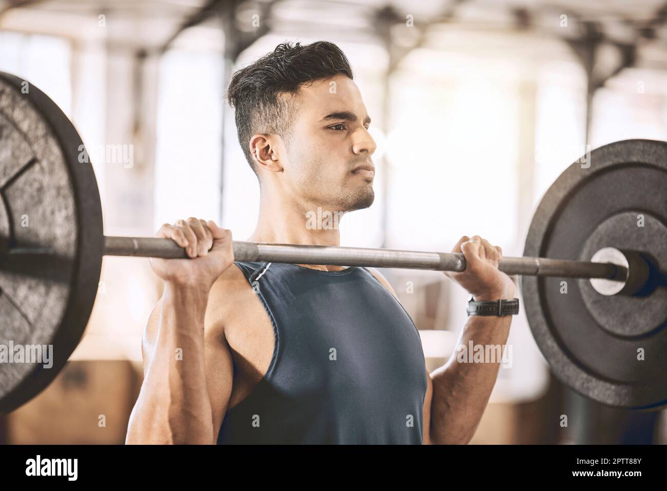 Fokussierter Aufbauhersteller, der schwere Gewichte hebt. Aktiver Sportler baut Armmuskeln mit einer schweren Hantel auf. Ein starker Trainer, der seine Trainingsroutine in der gy macht Stockfoto