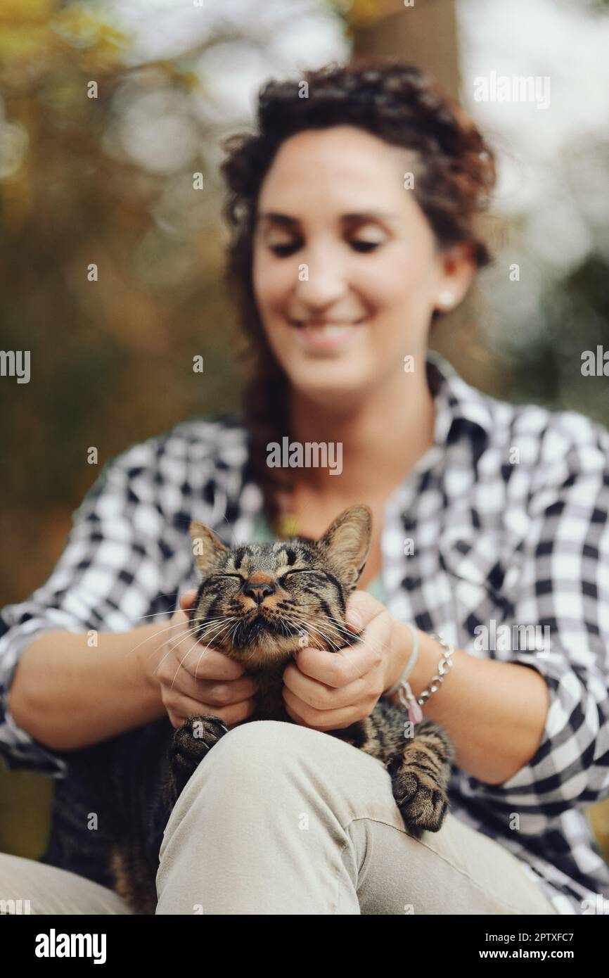 Ein normales Mädchen schlägt eine normale Katze im normalen Wald. Ist nicht alles außergewöhnlich außergewöhnlich? Kuscheln mit Tieren ist entspannend. Haustiertherapie oder einfach nur Genie Stockfoto