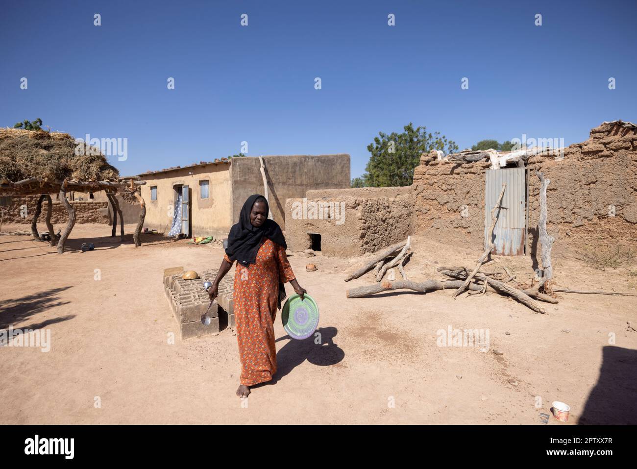 Afrikanische Frau, die durch ihr Wohngebiet in der Region Segou, Mali, Westafrika, läuft. 2022 Dürre und Hungerkrise in Mali. Stockfoto