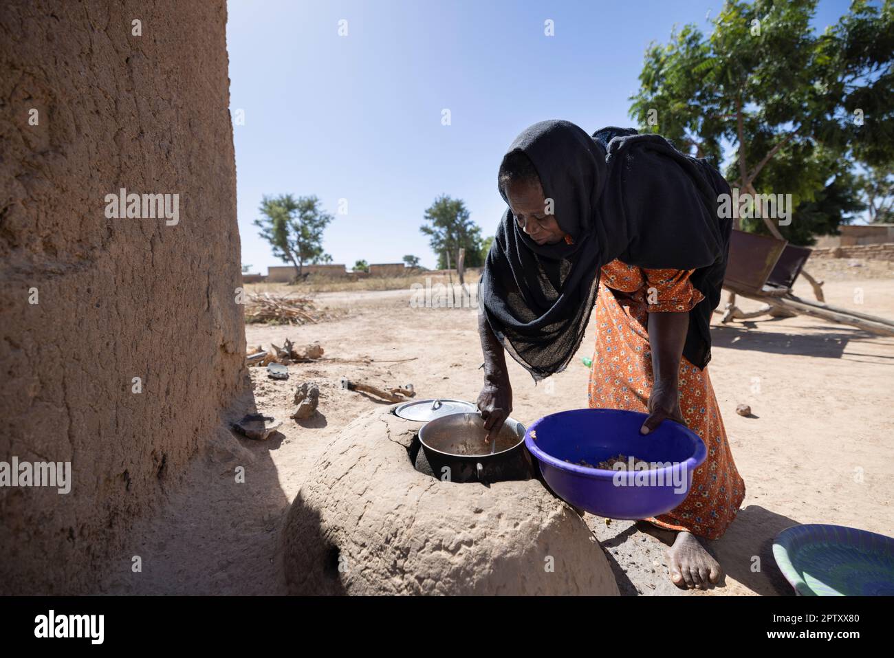 Frau kocht Essen über einem Erdschlammofen in Segou Region, Mali, Westafrika. 2022 Dürre und Hungerkrise in Mali. Stockfoto