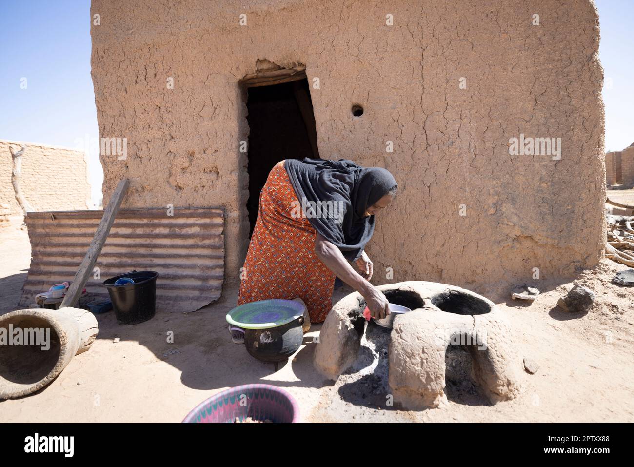 Eine ältere Frau kocht vor ihrem Haus in der Region Segou, Mali, Westafrika, über einem erdstämmigen, hausgemachten Herd. 2022 Dürre und Hungerkrise in Mali. Stockfoto