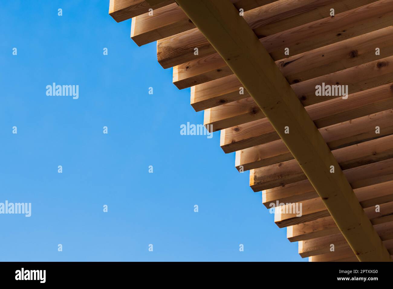 Abstraktes parametrisches Architekturfoto. Die neue Holzdachkonstruktion findet tagsüber unter blauem Himmel statt. Hintergrundtextur Stockfoto