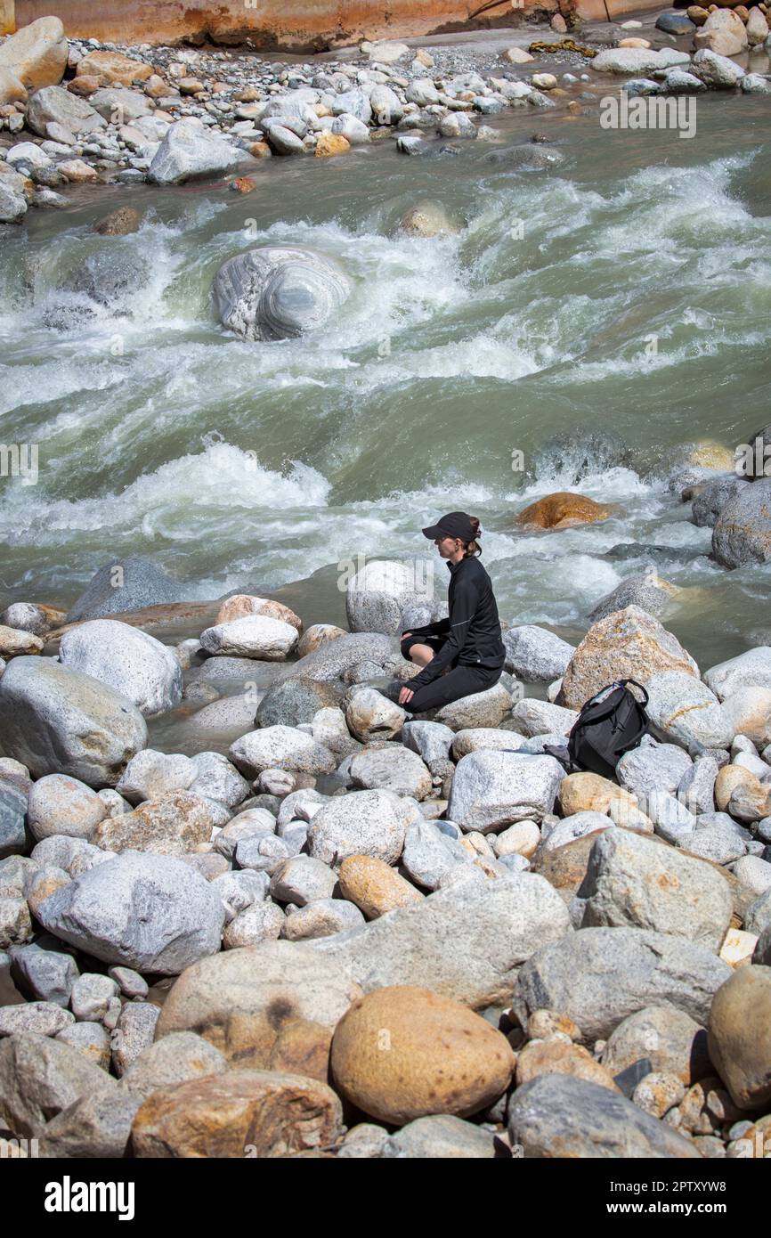 Indien, Uttarakhand, Gangotri. Himalaya. Wallfahrtsort. Bhagirathi-Fluss, Quelle von Ganga, Ganges-Fluss. Frau, Ausländerin, meditierend. Stockfoto