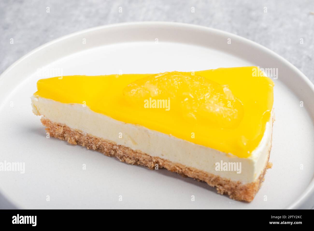 Dreieckiger Käsekuchen mit Zitrone auf einem weißen Teller Stockfoto