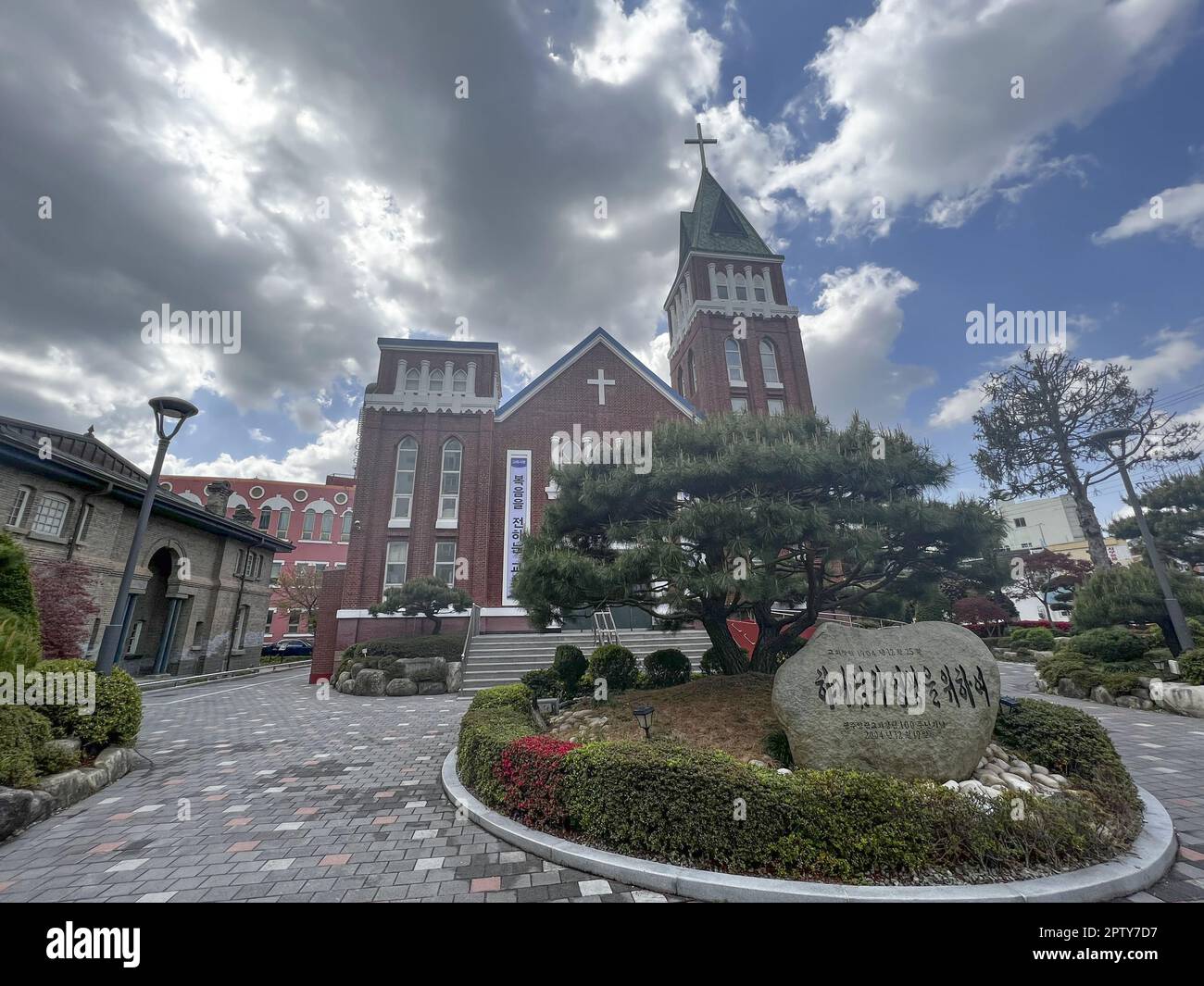 Die rote Backsteinmauerkirche „Middle“ Yangnim hat eine unberührte Zufahrt mit sorgfältig geschnittenen Bäumen und Blumenbeeten, Yangnim-dong, Südkorea, 08. April 2023. 08APR23 SCMP / Erika Na Stockfoto