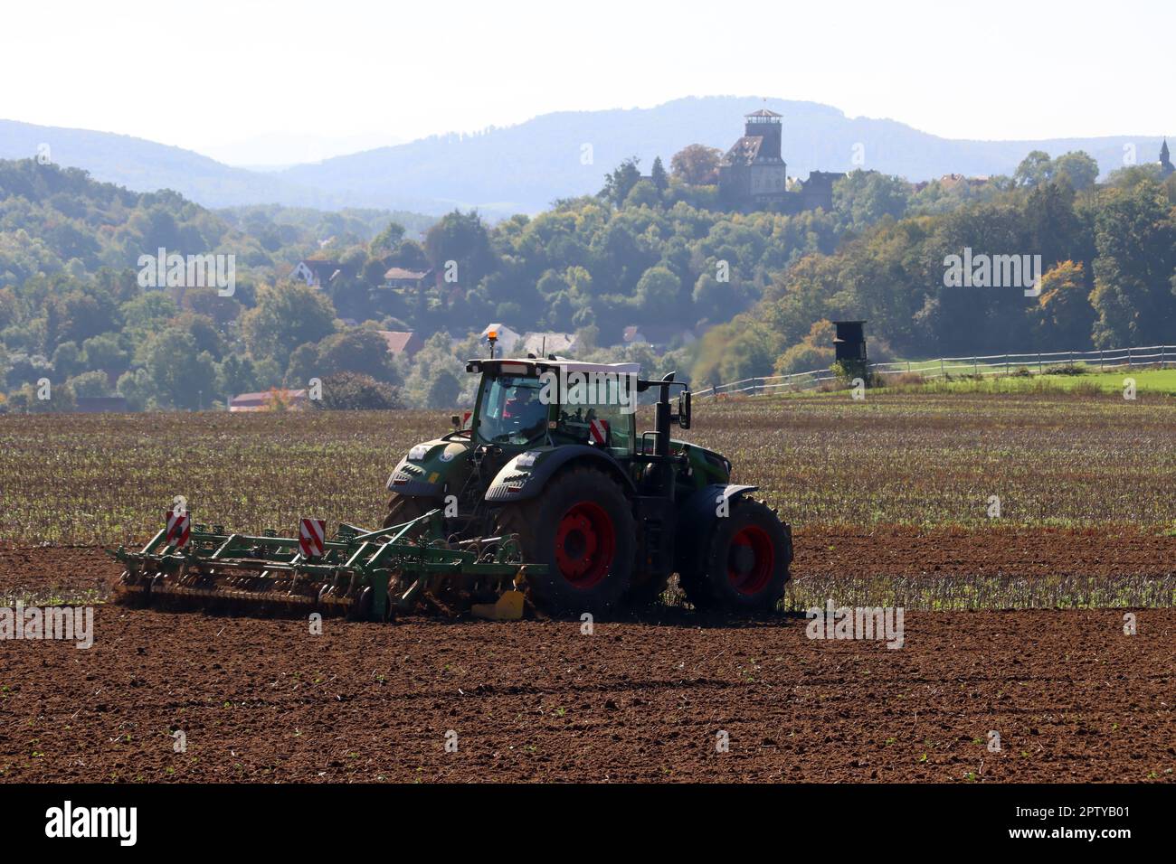Landwirt eggt das Feld, im Hintergrund Burg Trendelburg, Hessen, Deutschland Stockfoto