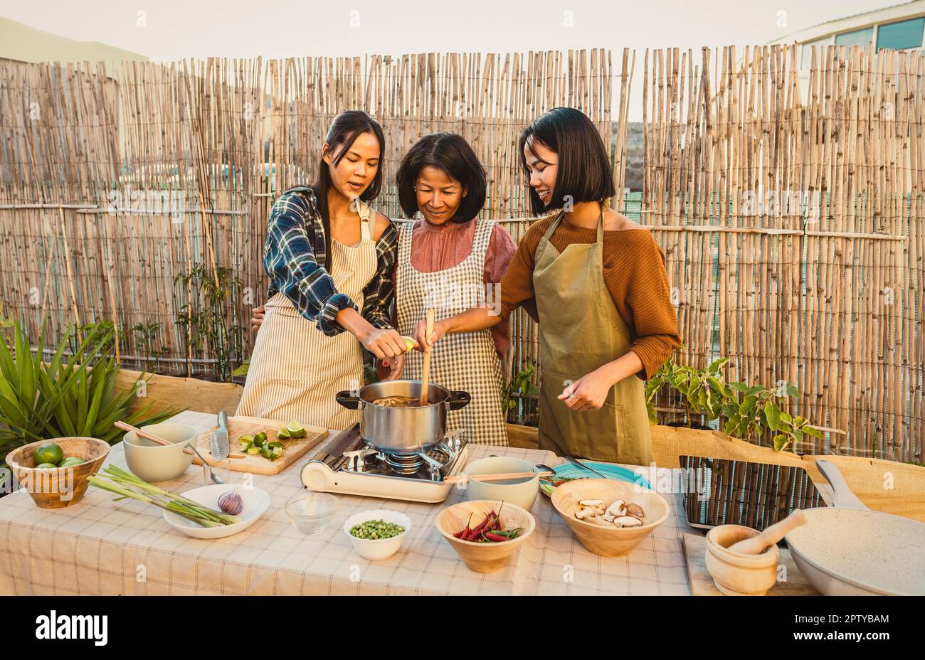 Glückliche thailändische Familie, die Spaß dabei hat, Suppenrezepte zusammen auf der Terrasse des Hauses zuzubereiten Stockfoto