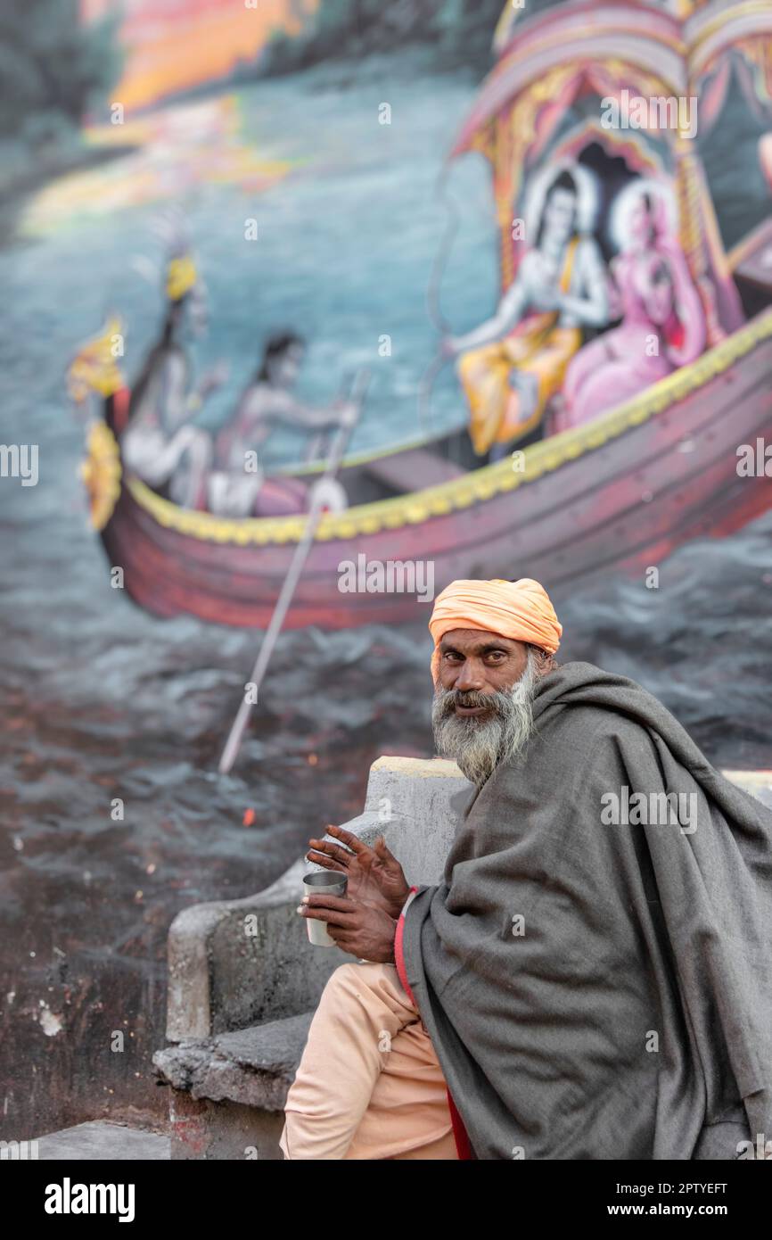 Indien, Uttarakhand, Rishikesh, Sadhu, heiliger Mann, Vor dem Wandgemälde. Stockfoto