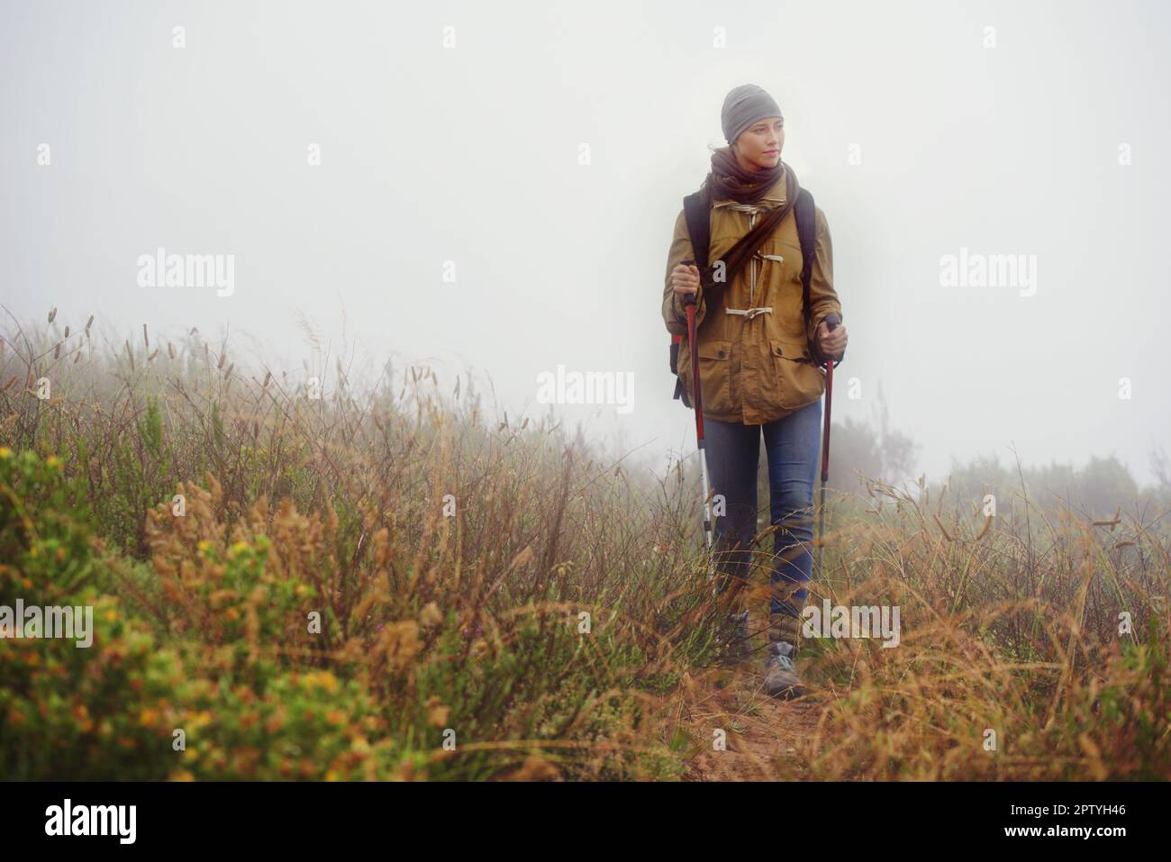 Allein in der Wildnis. Gesamtaufnahme einer jungen Frau, die an einem bedeckten Tag auf einem Pfad wandert Stockfoto