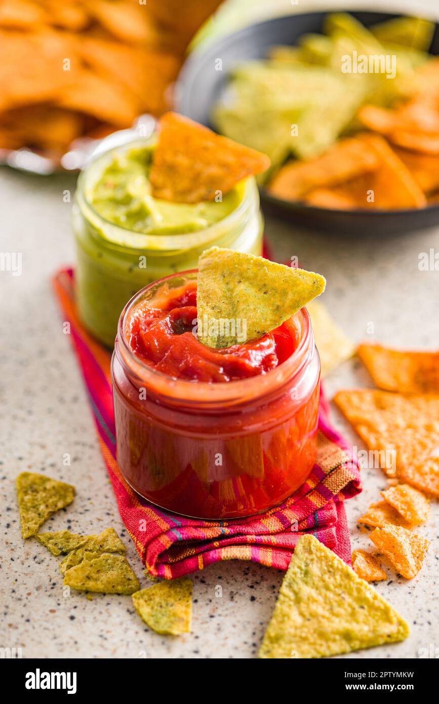 Rote und grüne Salsa mit Tortilla-Chips auf dem Küchentisch. Stockfoto