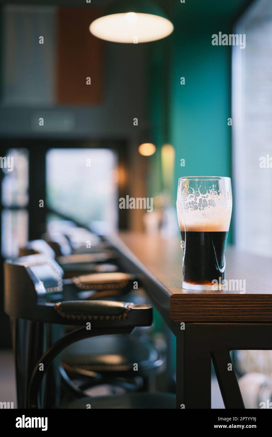 Vertikale Aufnahme, Nahaufnahme eines Glases Bier auf der Theke, selektiver Fokus. Balkenansicht, verwacklungsfreier Fokus, Idee zur Balkendekoration oder Foto für den Innenbereich Stockfoto