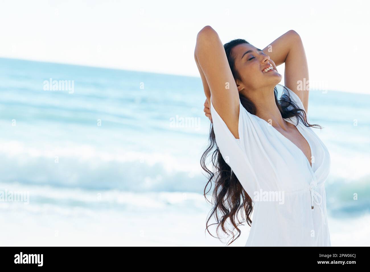 Ich fühlte mich noch nie so frei. Schöne Frau am Strand mit erhobenen Armen Stockfoto