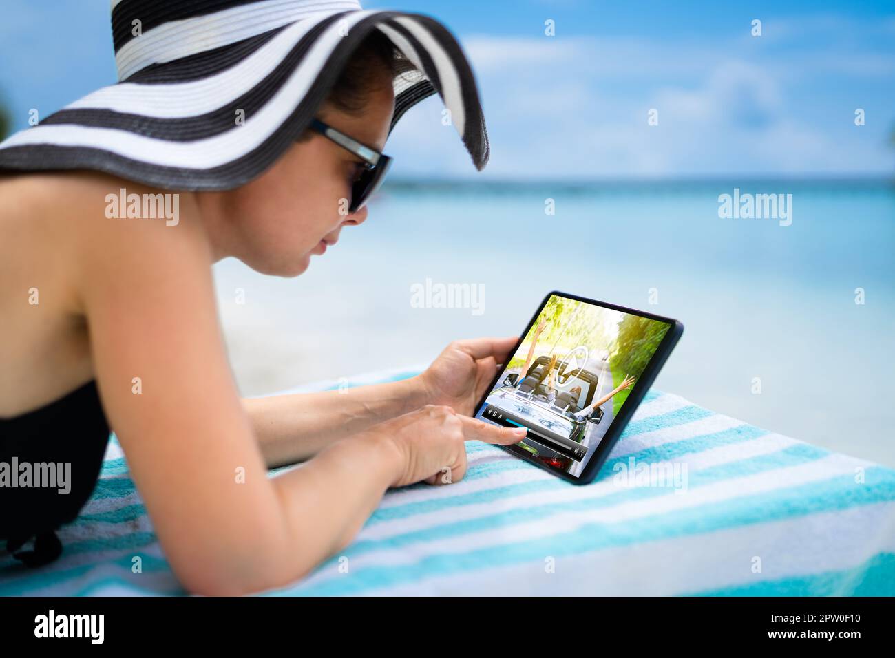 Frau, die sich TV-Film oder Video auf einem Tablet am Strand ansieht Stockfoto