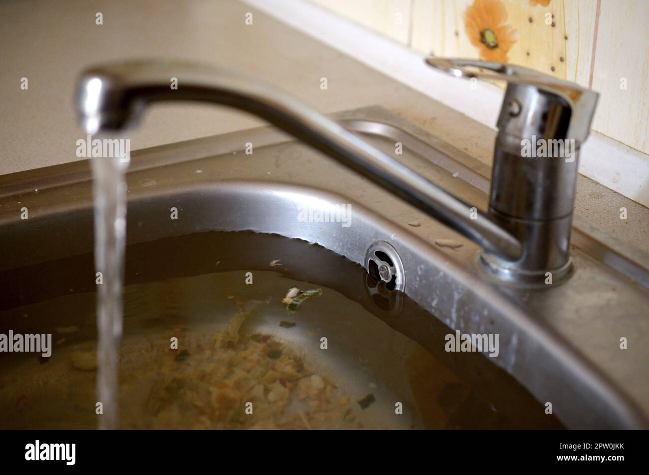 Edelstahl Waschbecken Stecker Bohrung close up voller Wasser und Partikel von Essen. Überquellenden Spüle, verstopften Abfluß. Probleme mit der Wasserversorgung Stockfoto