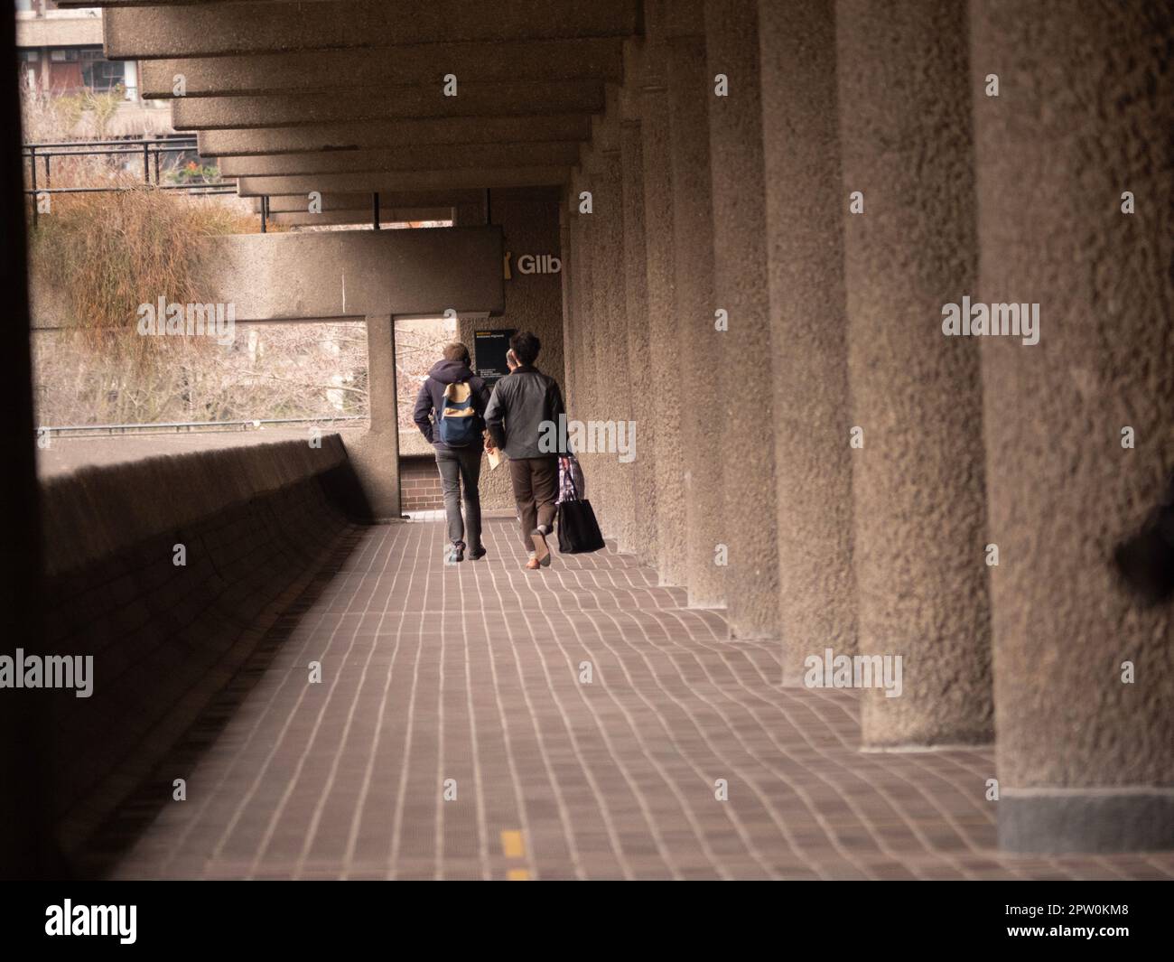 Fußgänger gehen den Andrewes Highwalk entlang, im Barbican Estate der City of London Stockfoto