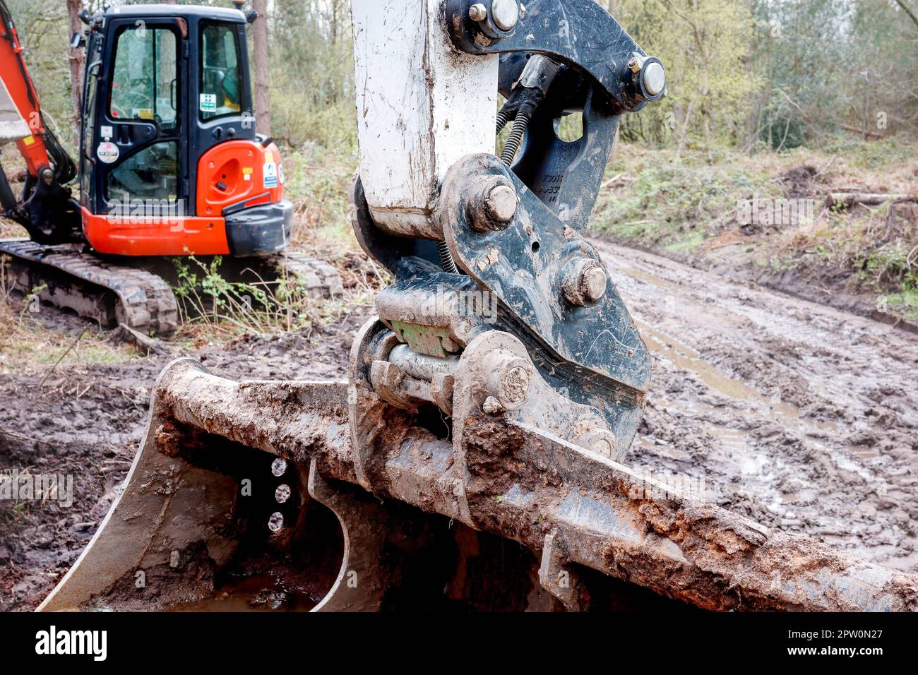 Cheshire UK April 2023 Kipperwagen und Bagger reparieren einen Weg in Delamere Forrest, während sie einen Löffel mit Erde füllen, Teil der Baumaschine U Stockfoto