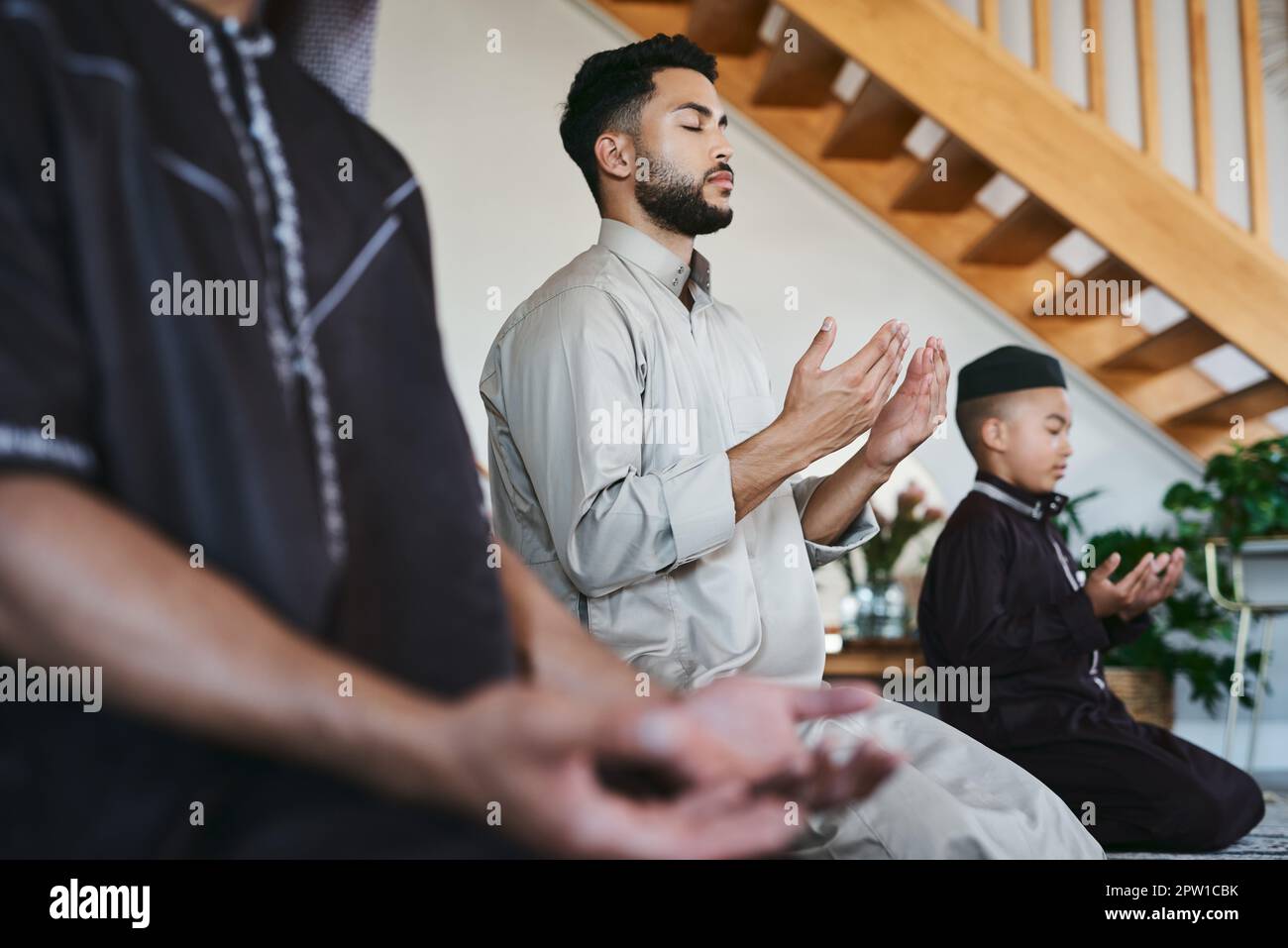 Muslimische Familie betet zu Hause mit geschlossenen Augen während fajr, dhuhr, asr, maghrib oder Isha. Üben von Religion und kultureller Tradition zu dienen Stockfoto