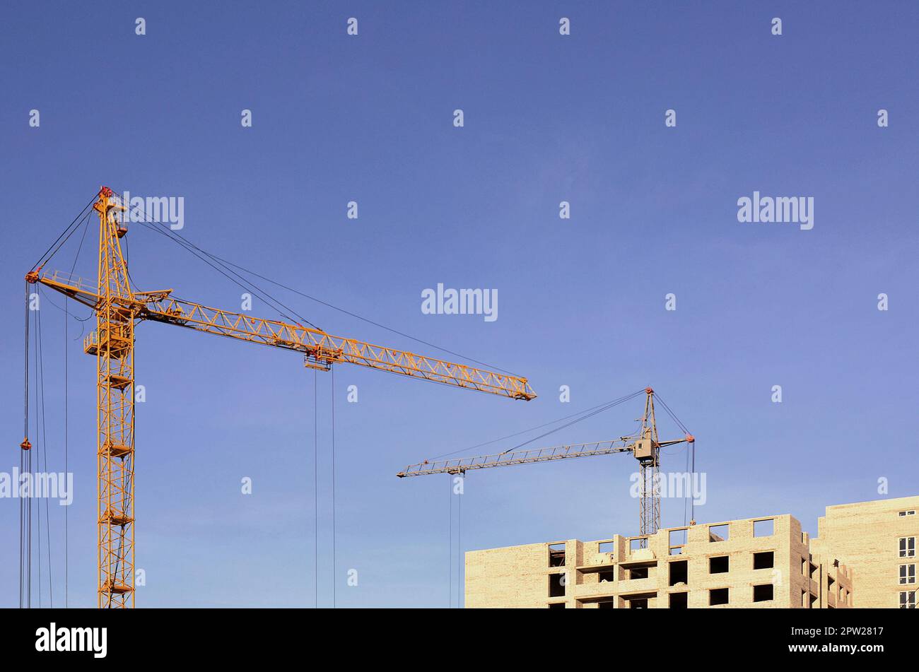 Die hohen Kräne im Inneren Platz für mit hohen Gebäuden im Bau eines klaren blauen Himmel. Kran und Gebäude arbeiten, Fortschritte mit copyspa Stockfoto