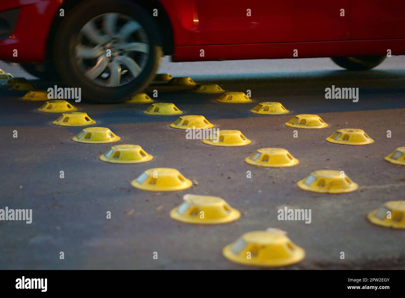 Gelb reflektierende Stollen auf einer Straße in der Stadt, als verkehrsberuhigende Maßnahme verwendet. Stockfoto