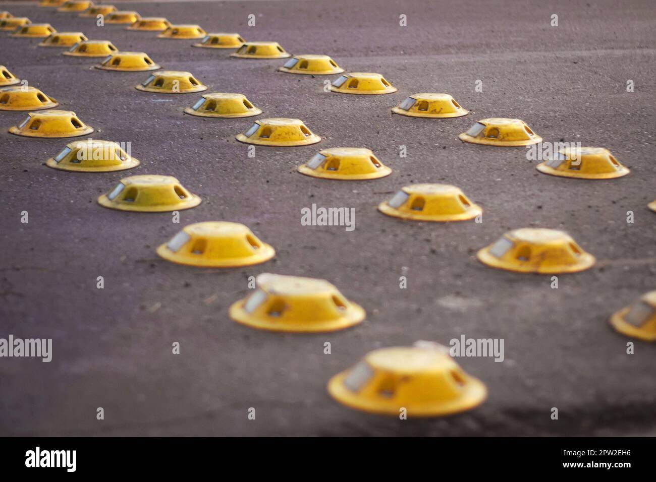 Gelb reflektierende Stollen auf einer Straße in der Stadt, als verkehrsberuhigende Maßnahme verwendet. Stockfoto