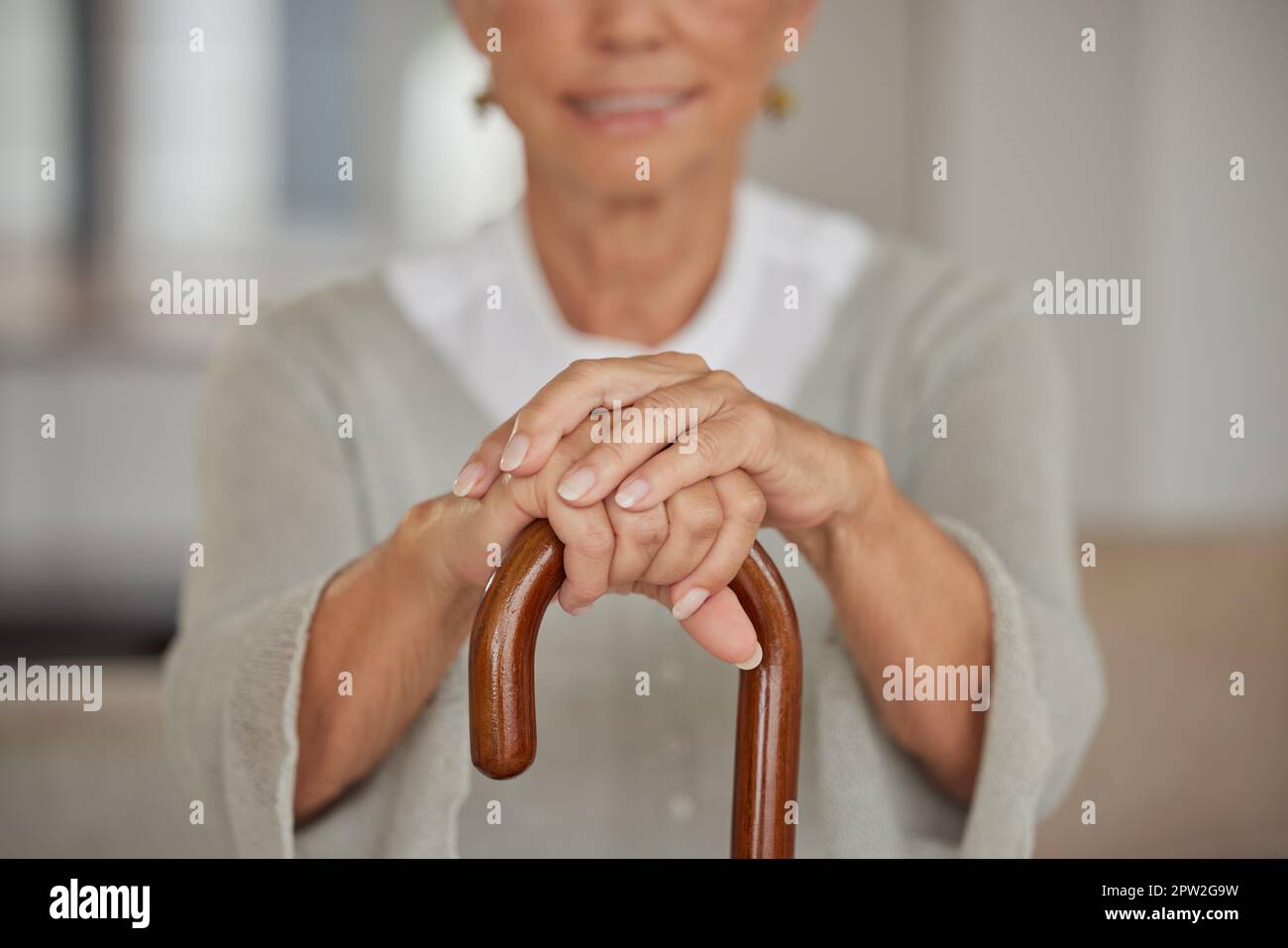 Ältere behinderte Frau, die einen Stock in einem Pflegeheim hält. Nahaufnahme einer älteren Dame, die eine Gehhilfe in der Hand hält und sich in einer Gesundheitseinrichtung entspannt Stockfoto
