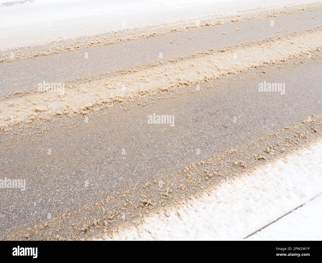 Schneeverwehungen am Straßenrand. Schlechtes Wetter und Verkehr. Schnee auf Asphalt. Schwierige Fahrbedingungen. Winterschlamm auf der Straße. Bremsweg Stockfoto