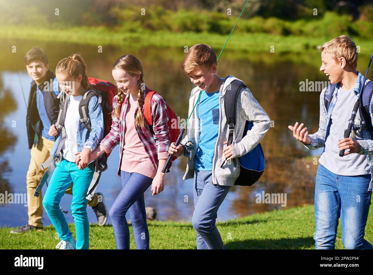 Bereit für ein Abenteuer. Eine Gruppe junger Freunde, die Rucksäcke tragen und zusammen an einem See spazieren gehen Stockfoto