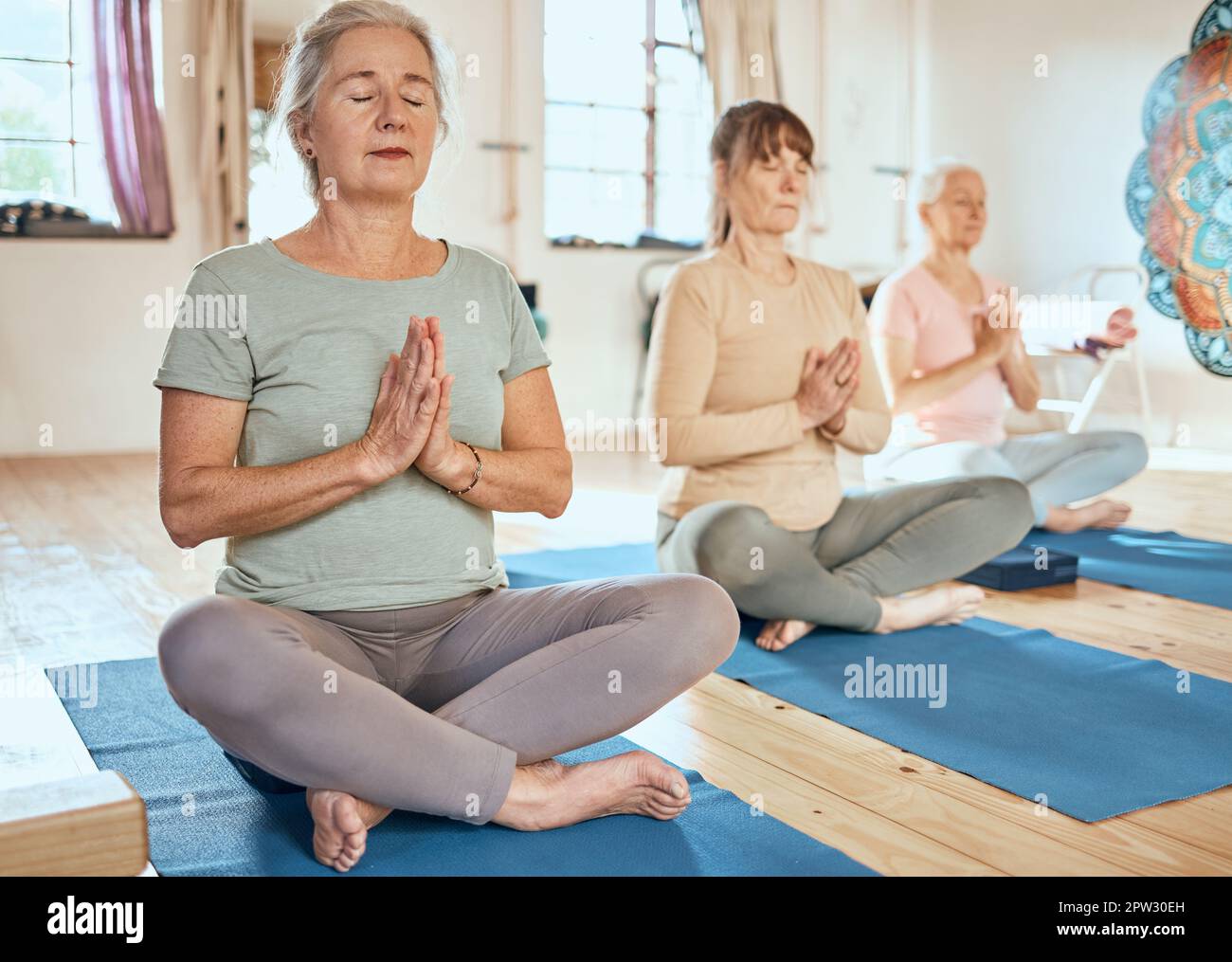 Yoga, Gebet und Meditation, Freunde und Frauen zu Hause für spirituelle Gesundheit und Wohlbefinden. Zen, Chakra-Energie und Gruppe von reifen Frauen Training in Stockfoto