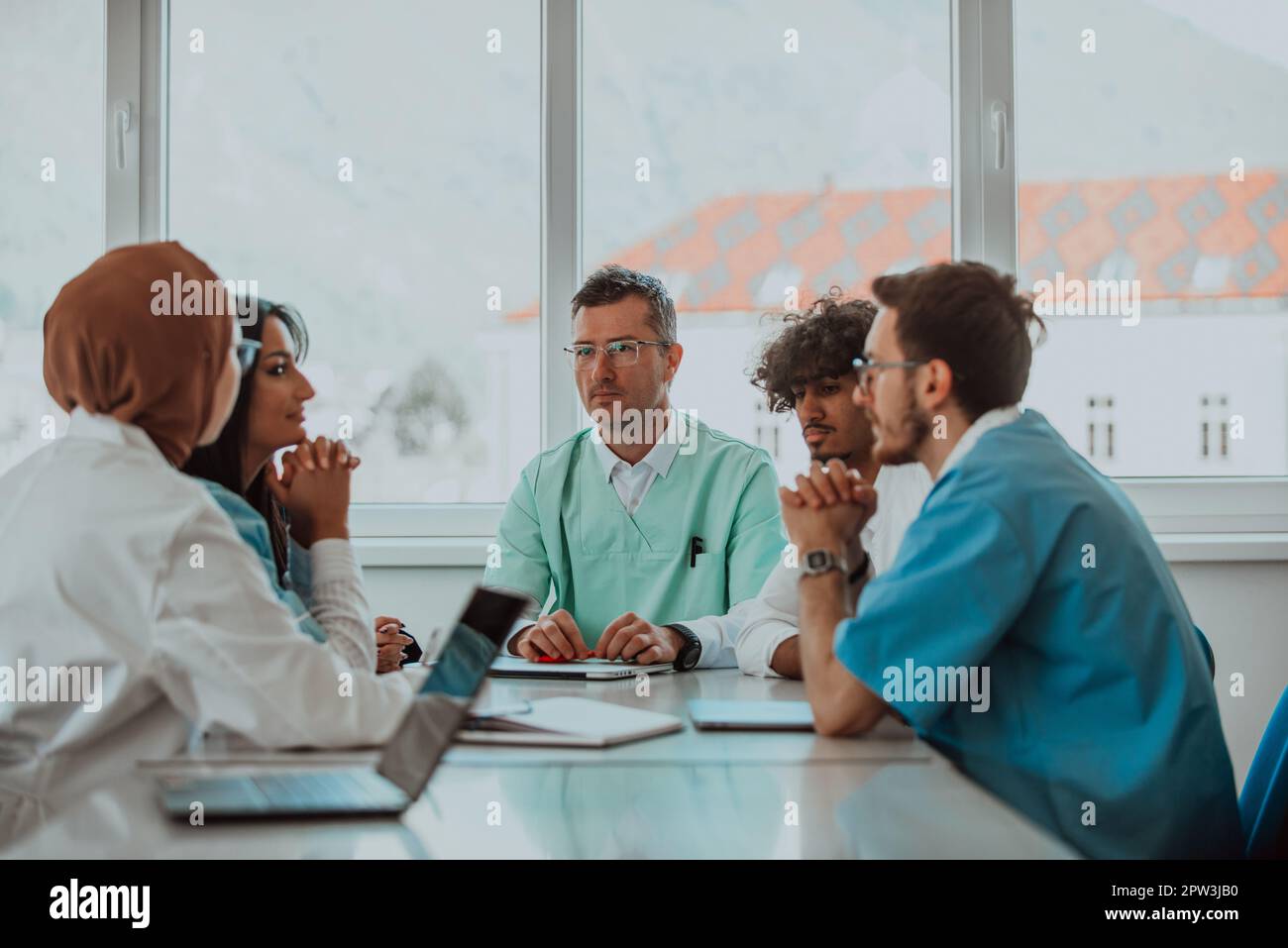 Eine Gruppe von multiethnischen medizinischen Fachkräften, darunter Ärzte, Chirurgen und Krankenschwestern, sind in einem Krankenhaus zusammengekommen, um die Patientenversorgung und zu diskutieren Stockfoto