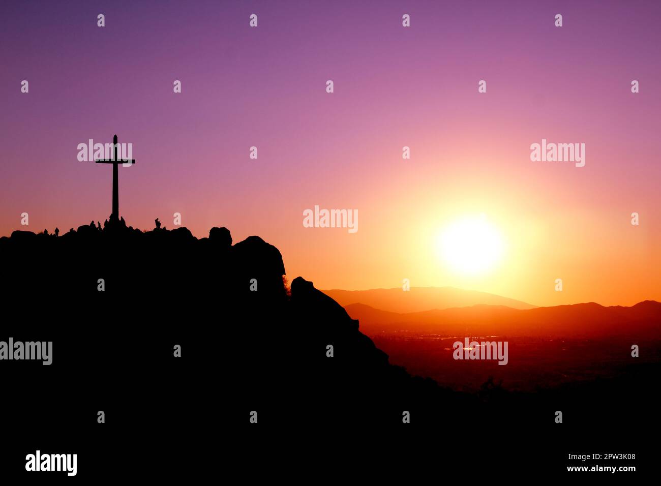 Überqueren Sie den Gipfel eines Berges mit Silhouetten von Menschen und einem violetten, orangefarbenen und gelben Sonnenuntergang Stockfoto