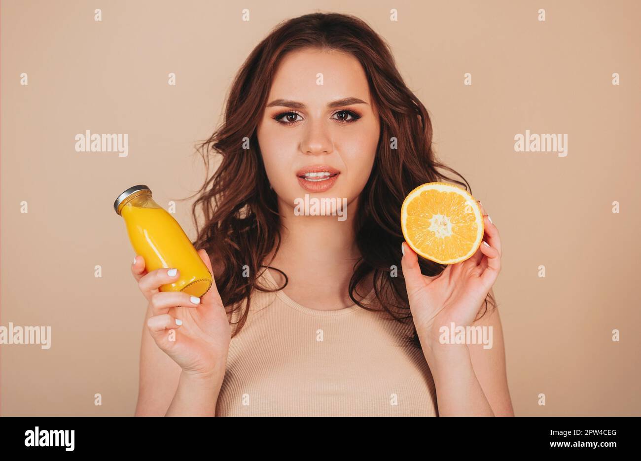 Brünett weiblich tragen beige Outfit hält orange Scheibe und Boden Mit Orangensaft in den Händen Stockfoto