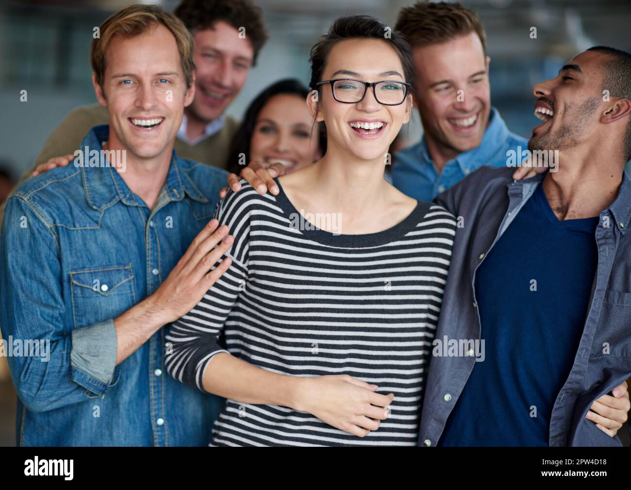 Die Art von Arbeitsumfeld, das herausragende Beziehungen inspiriert. Eine lächelnde Gruppe von Kollegen, die in einem Büro stehen Stockfoto