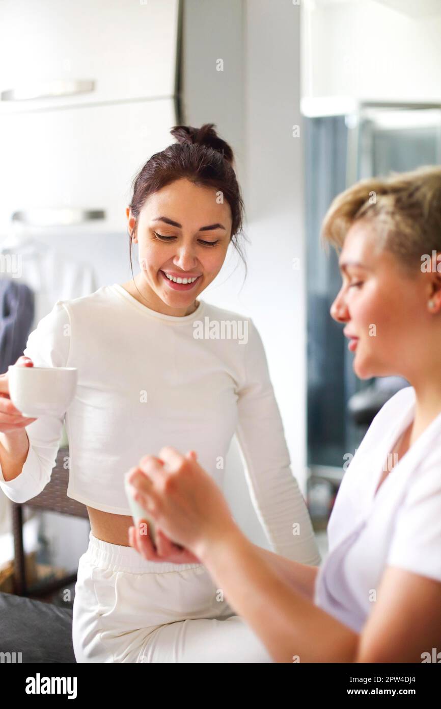 Weibliche Kosmetikerin, die während der Anwendung feuchtigkeitsspendende Creme auf die Hände des Kunden Hautpflege Routine im Salon Stockfoto
